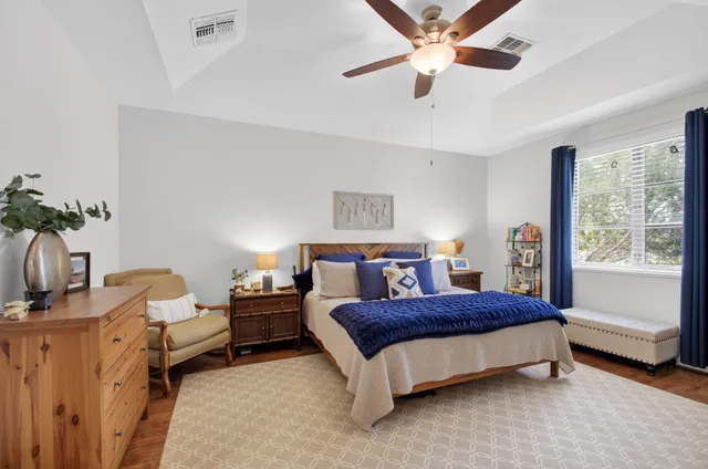a bedroom with a bed a dresser and a chandelier
