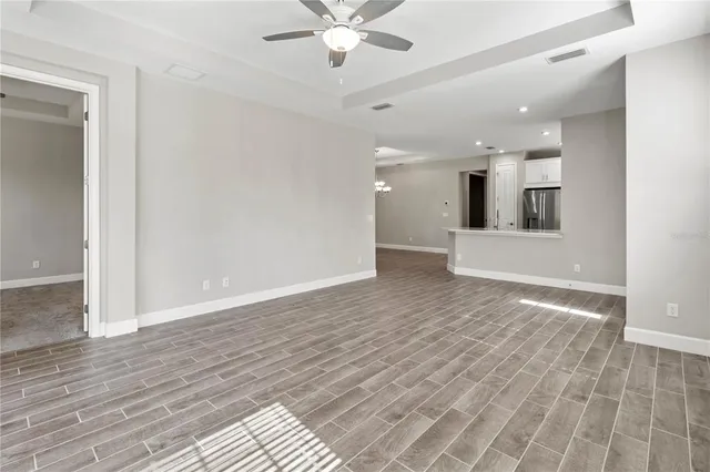 a view of an empty room with wooden floor and a ceiling fan