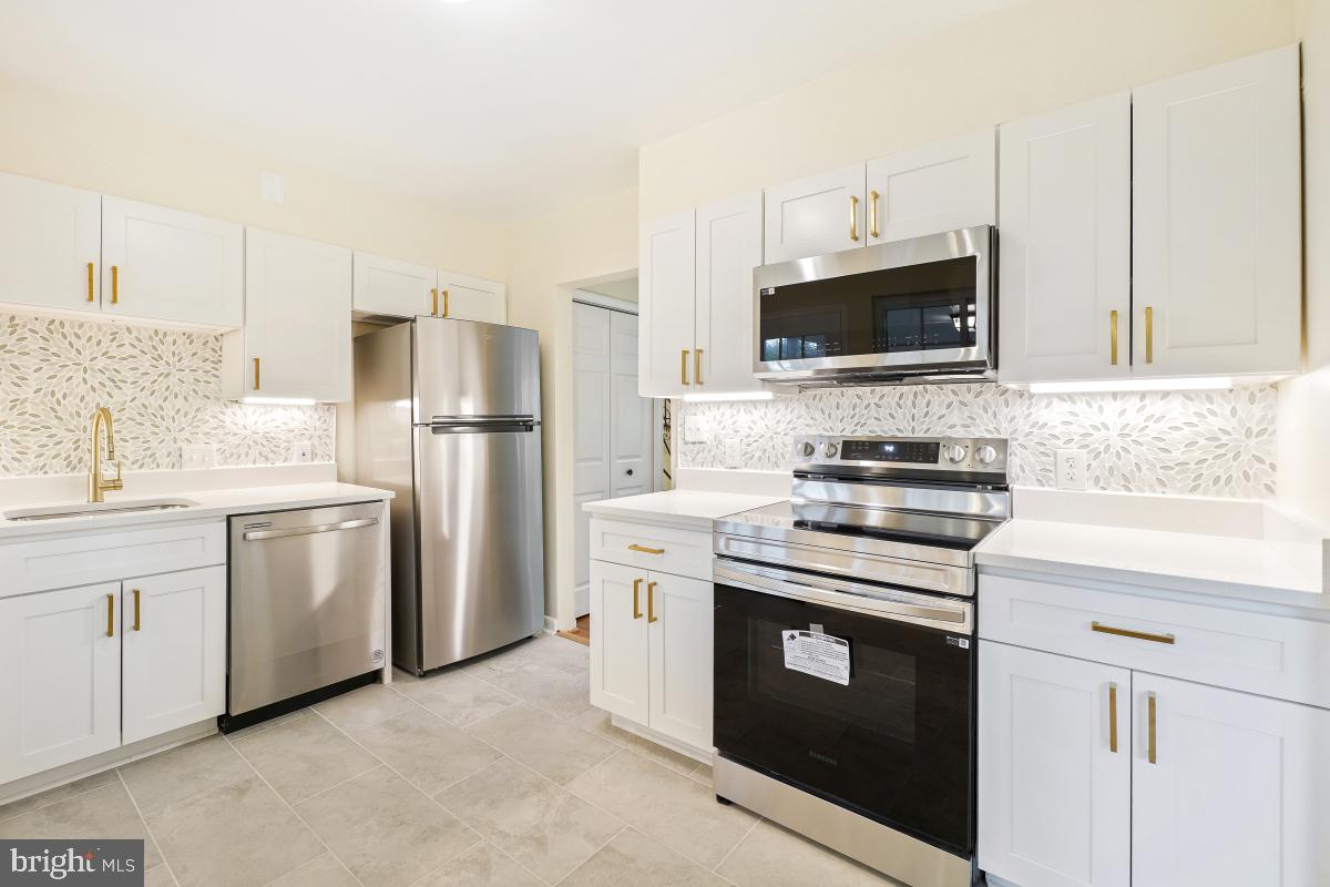 804 Gregorio Drive Silver Spring, MD 20901 - Photo 12 of 33 a kitchen with white cabinets and stainless steel appliances
