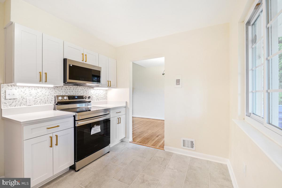 804 Gregorio Drive Silver Spring, MD 20901 - Photo 13 of 33 a kitchen with granite countertop a stove and a microwave