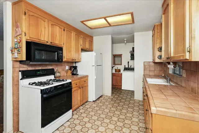 a living room with stainless steel appliances furniture a rug and a kitchen view
