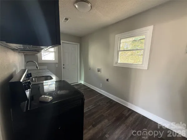 a kitchen with granite countertop a stove top oven a sink dishwasher and a microwave oven with wooden floor