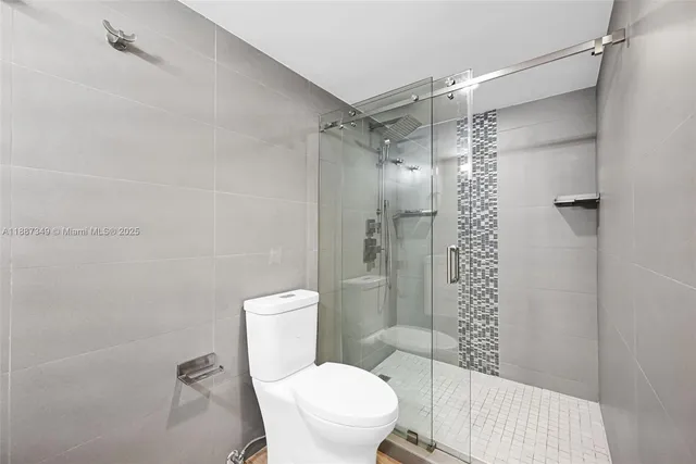 a white toilet sitting next to a shower