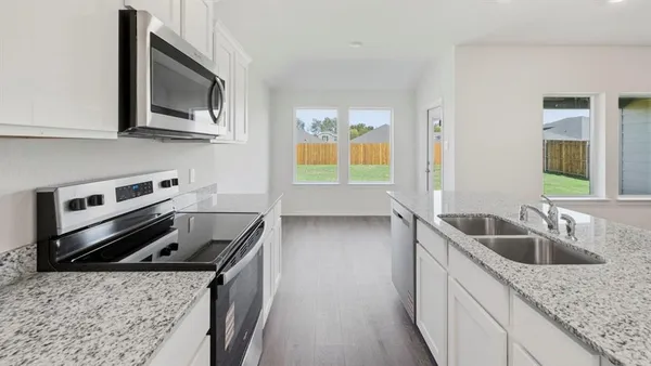 a large kitchen with stainless steel appliances granite countertop a sink a stove and a wooden floors