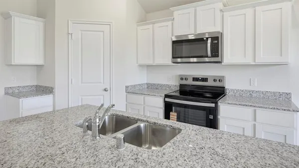 a view of a kitchen with kitchen island a sink wooden floor and a large window