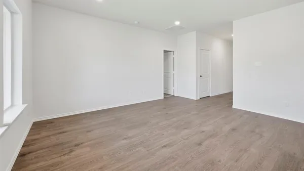 a view of an empty room with wooden floor and windows