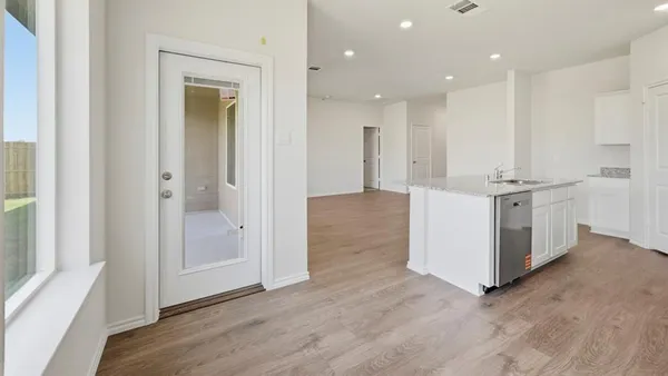 a kitchen with cabinets wooden floor and stainless steel appliances