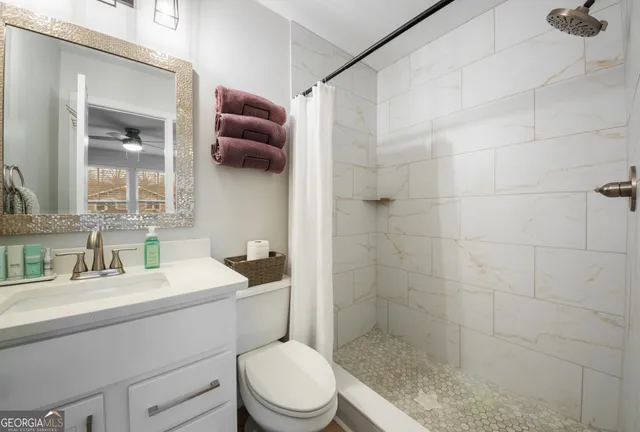 a bathroom with a sink a toilet a mirror and shower