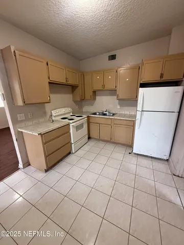 a kitchen with a stove a sink dishwasher and a refrigerator