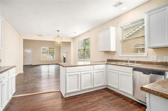 a kitchen with stainless steel appliances granite countertop a stove a sink and white cabinets with wooden floor