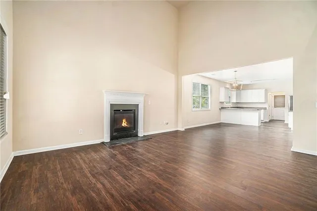 an empty room with wooden floor fireplace and windows