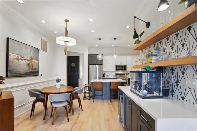 a kitchen with stainless steel appliances kitchen island granite countertop a table chairs and a refrigerator