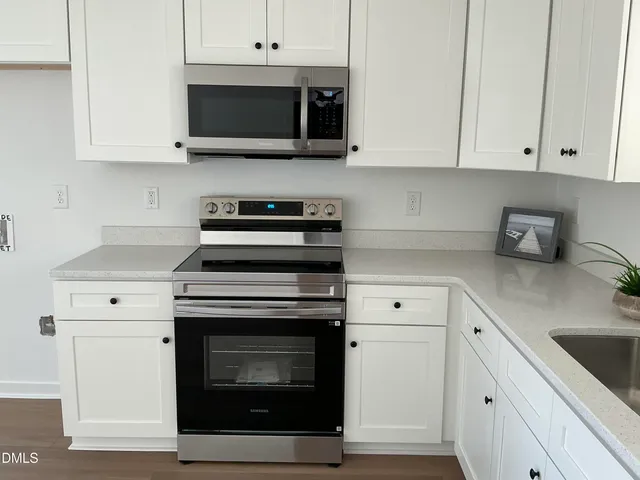 a kitchen with white cabinets and appliances
