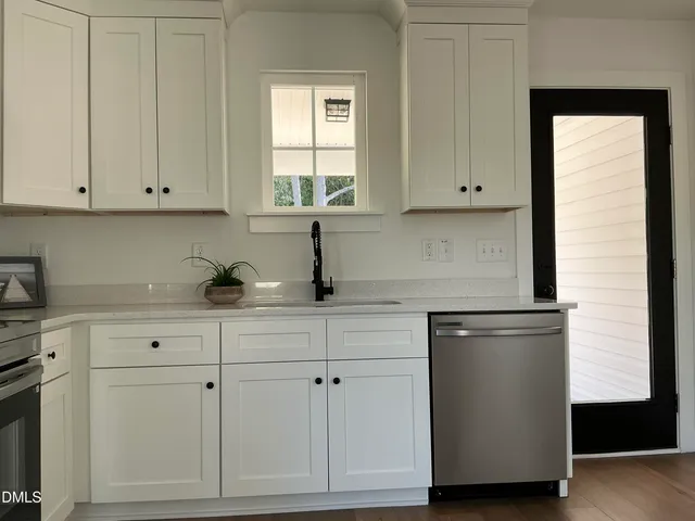 a kitchen with white cabinets and a window