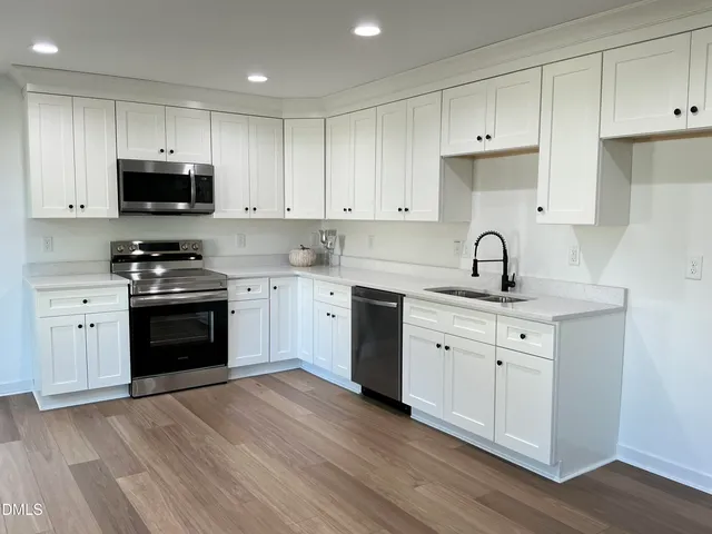 a kitchen with granite countertop a sink cabinets and stainless steel appliances