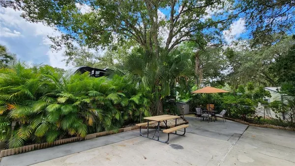 a backyard of a house with table and chairs under an umbrella