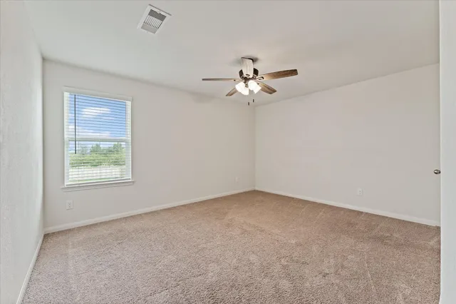 an empty room with a chandelier fan and windows