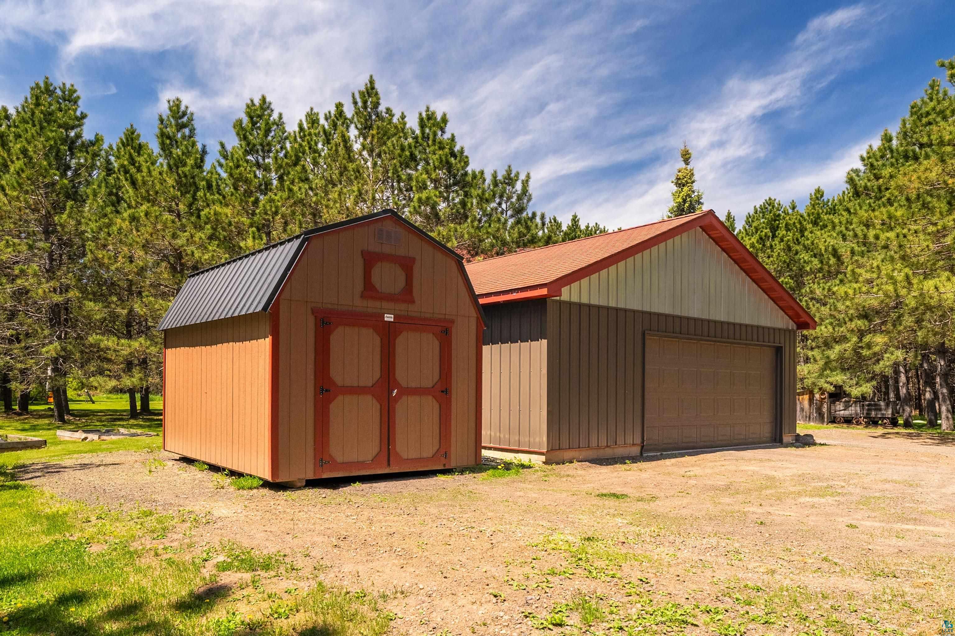 75 East Stark Road Esko, MN 55733 - Photo 69 of 87 Detached garage with a brown roll-up door and a shed with double doors, both featuring a natural wood tone finish