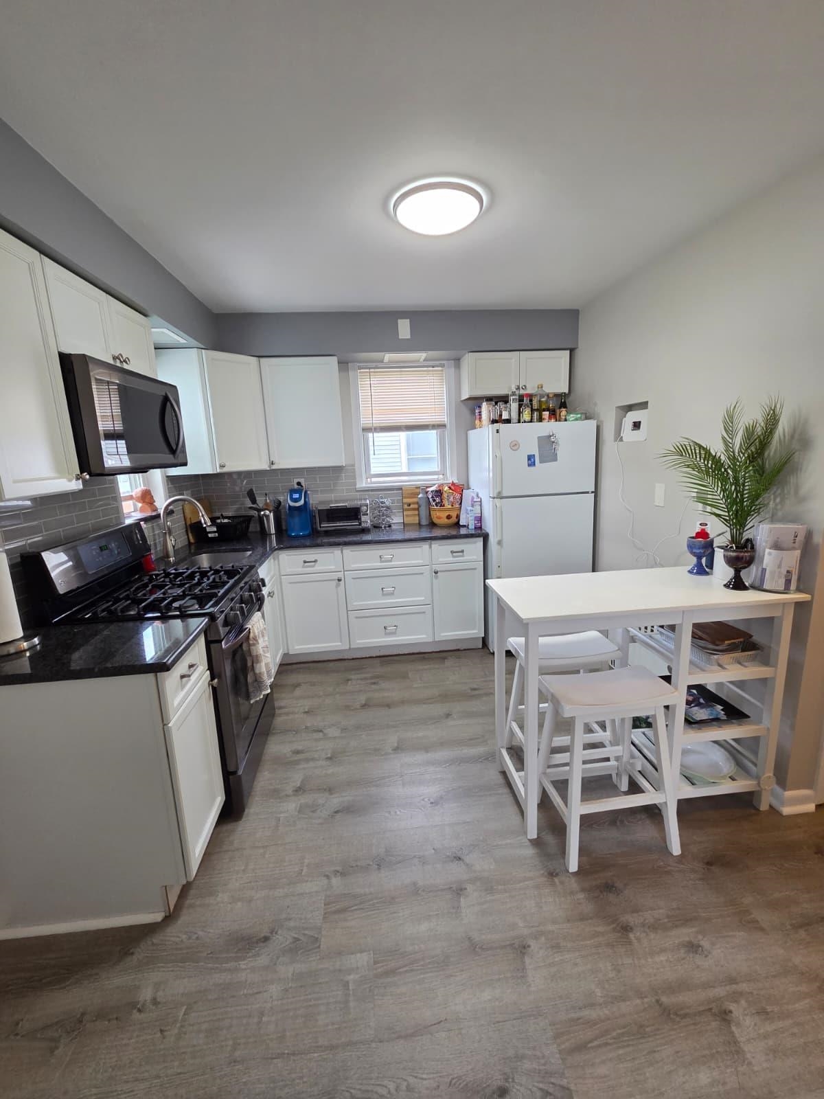 166 Carmita Avenue, Unit 2 Rutherford, NJ 07070 - Photo 3 of 27 a kitchen with a table chairs a sink dishwasher stove and cabinets