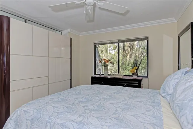 a bedroom with a large bed and a chandelier fan