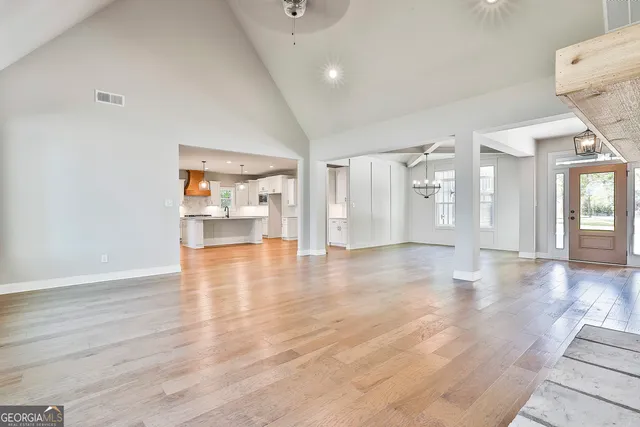 a large white kitchen with kitchen island a stove a sink cabinets and wooden floor