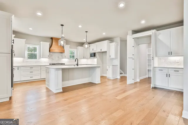 a kitchen with white cabinets appliances and wooden floor