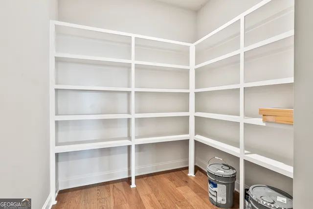 a view of an empty room with wooden floor and a view of bedroom
