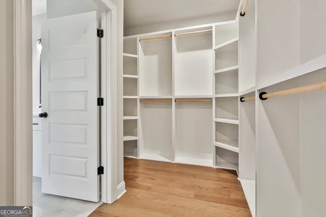 a view of a hallway with wooden floor and a bathroom