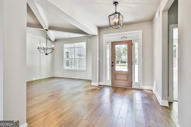 a view of an empty room with wooden floor and window