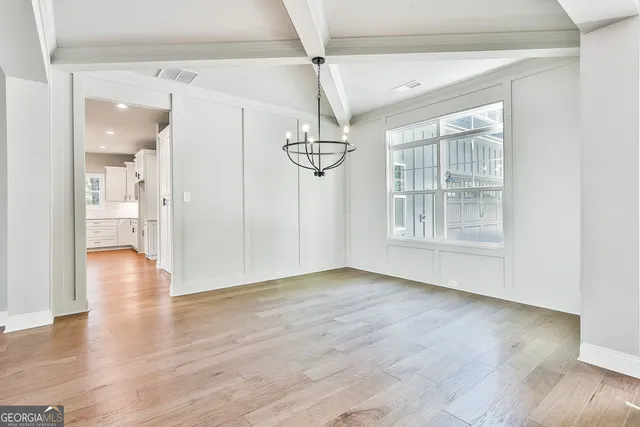 an empty room with wooden floor fireplace and windows