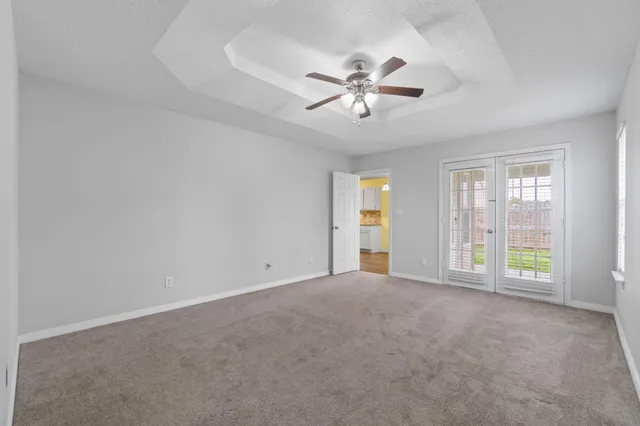 a view of an empty room with chandelier fan and fire place