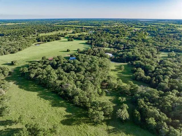 an aerial view of a houses with outdoor space and trees all around