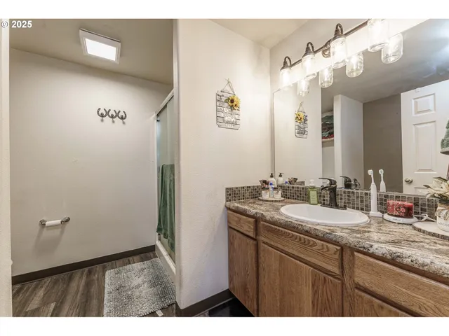 a bathroom with a granite countertop sink a mirror and a shower