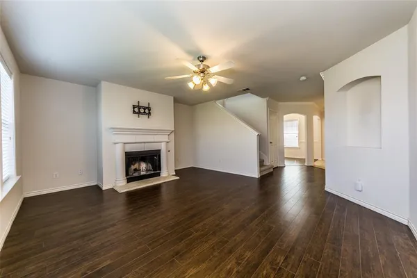 a view of an empty room with wooden floor fireplace and a window