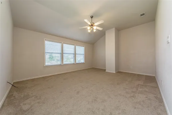 an empty room with chandelier fan and windows