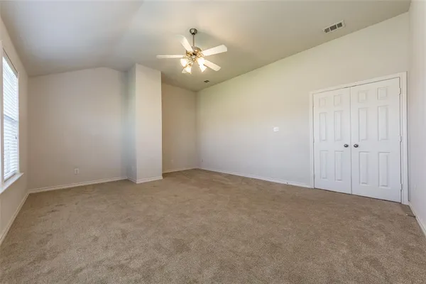 an empty room with a chandelier fan and windows