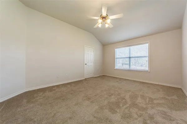 an empty room with a chandelier fan and windows