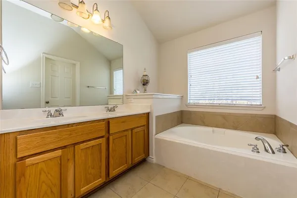 a bathroom with a tub a sink and mirror