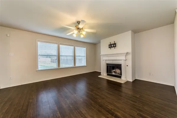 a view of an empty room with wooden floor fireplace and a window