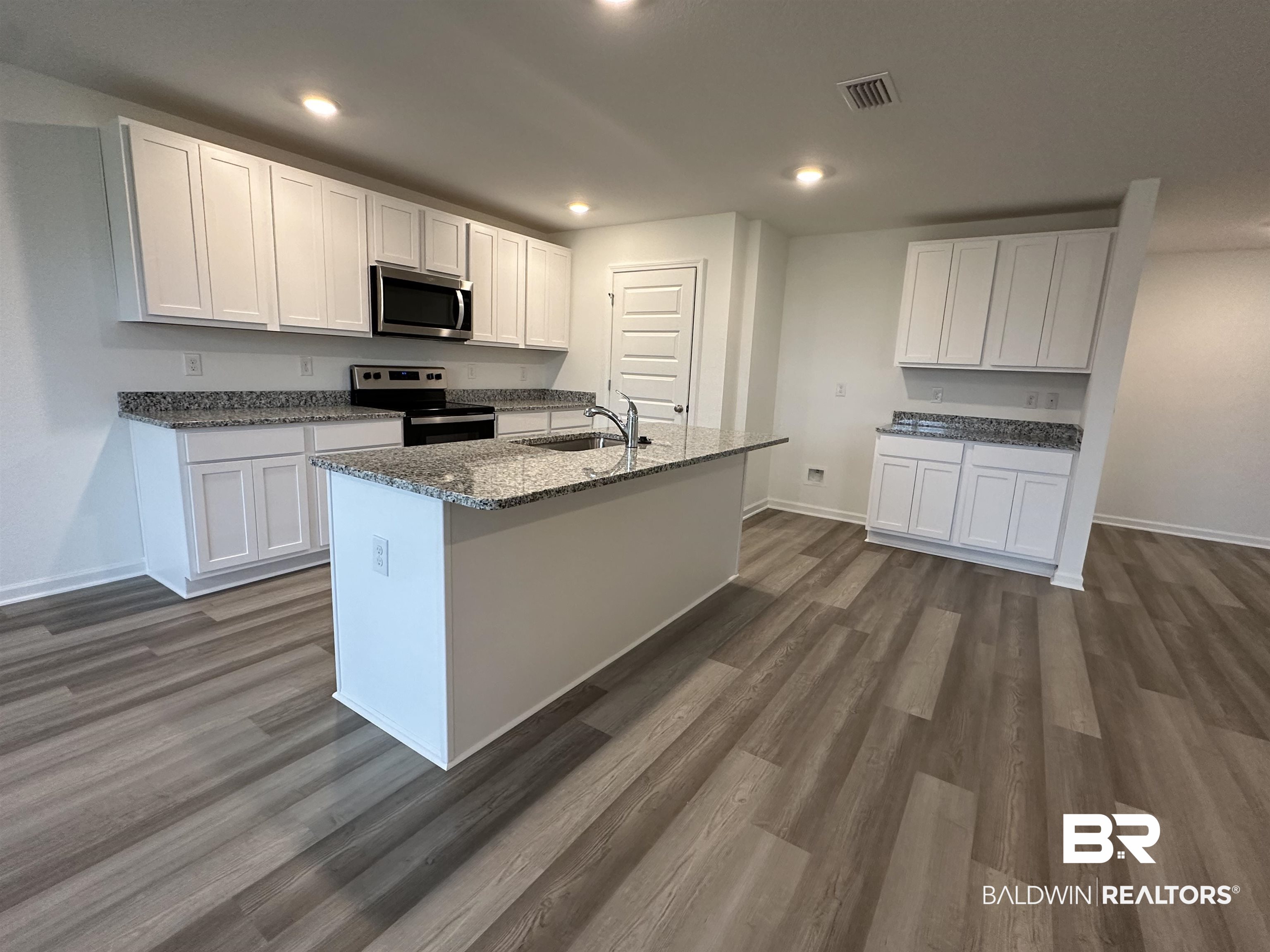 22275 Aleutian Avenue Foley, AL 36535 - Photo 7 of 72 Kitchen featuring stainless steel appliances, dark hardwood / wood-style flooring, sink, white cabinets, and a kitchen island with sink