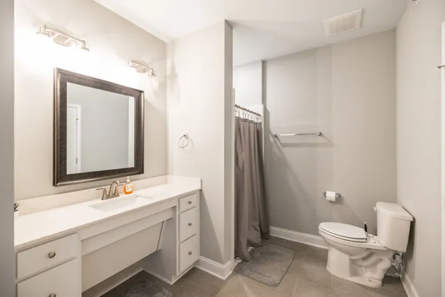 a bathroom with a toilet a sink a light fixture and a mirror