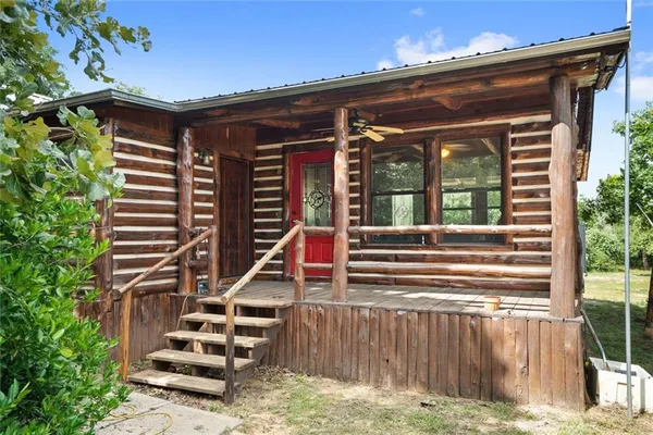 a view of a backyard with table and chairs potted plants and large tree