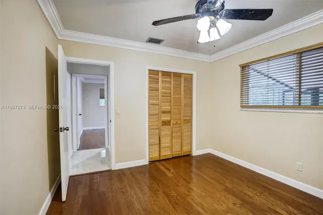 a view of an empty room with a window and wooden floor