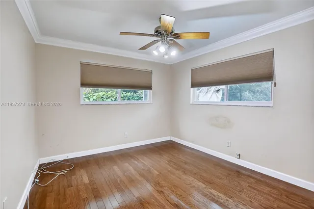 a view of an empty room with a window and wooden floor