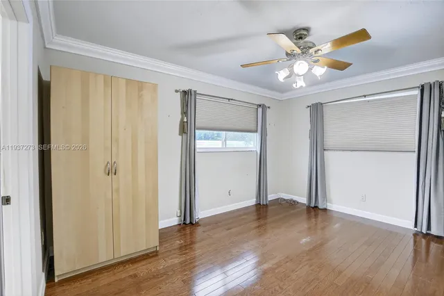 an empty room with wooden floor closet and windows