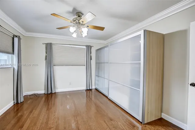 an empty room with wooden floor closet and windows