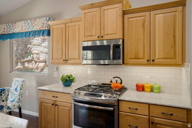 1587 Whitestone Drive St. George, UT 84790 - Photo 11 of 36 Kitchen featuring light wood cabinetry, stainless steel microwave, stainless steel range, light-toned countertops, and a white subway tile backsplash