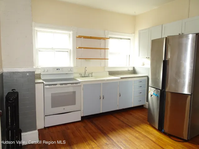 a kitchen with a white stainless steel appliances a sink cabinets and a window
