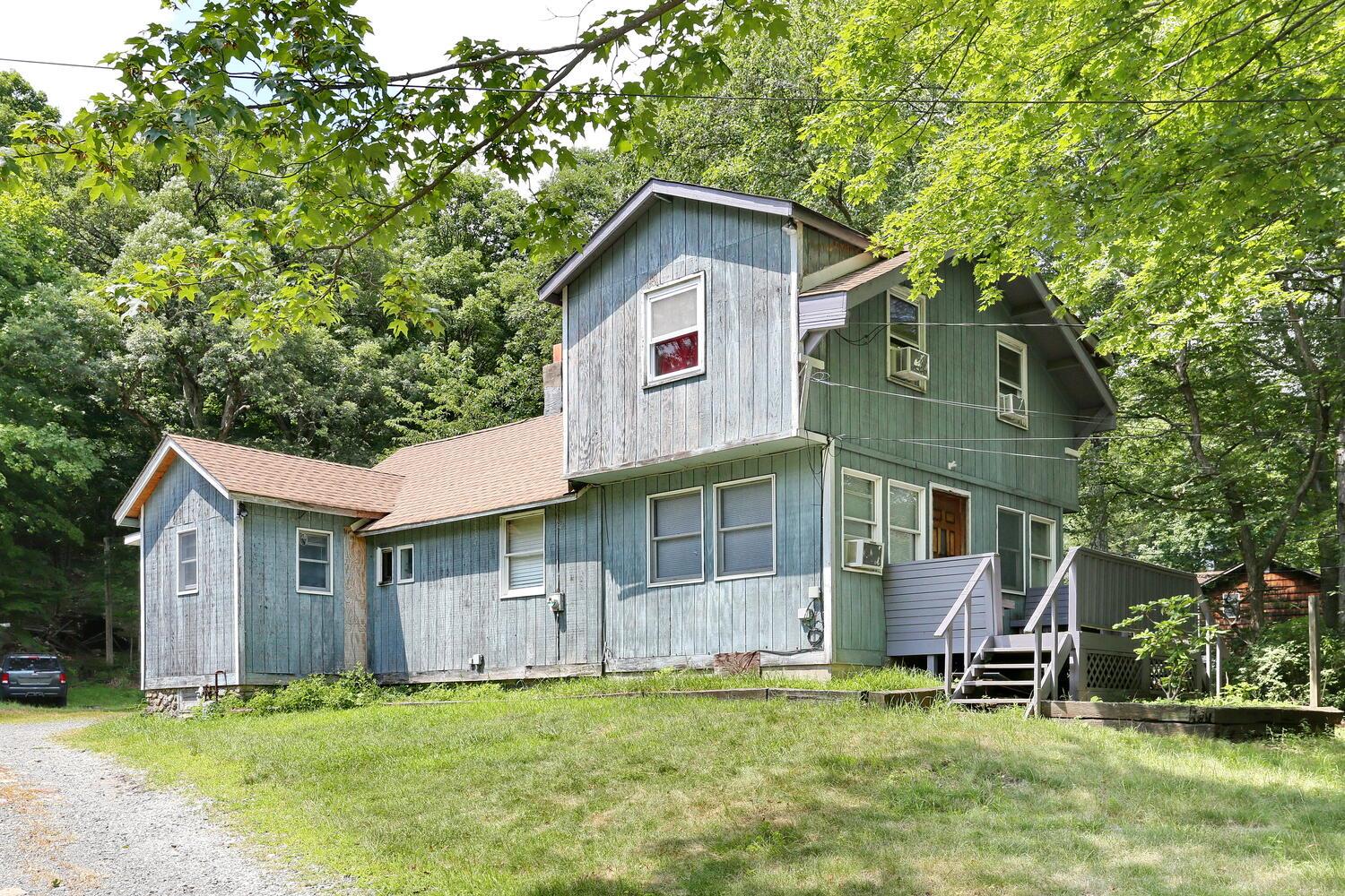 View of front of home featuring a front yard, a wooden deck, and a shingled roof