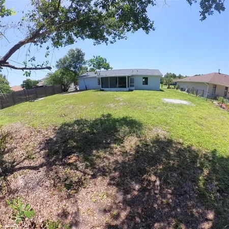 a view of a house with a big yard and large trees
